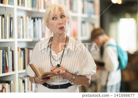 Senior woman choosing books in large bookstore 141898677