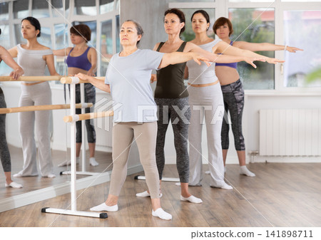 Senior woman maintaining second position at amateur ballet class Senior woman maintaining second position at amateur ballet class 141898711