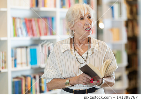 Senior woman choosing books in large bookstore Senior woman choosing books in large bookstore 141898767