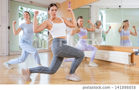 Fit women of different ages performing dynamic energetic dancing movements in modern loft studio Fit women of different ages performing dynamic energetic dancing movements in modern loft studio 141898858