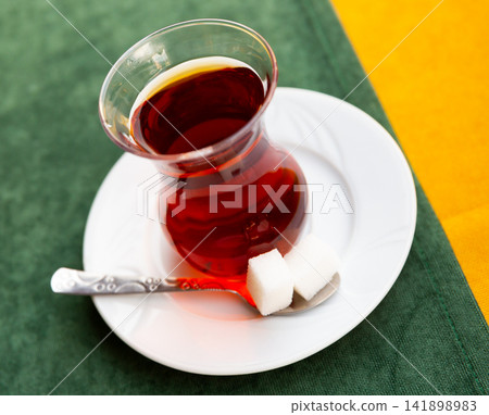 Close-up Of fresh hot Turkish tea with two sugar cubes Close-up Of fresh hot Turkish tea with two sugar cubes 141898983