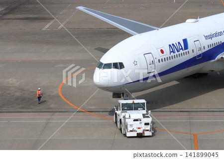 Pushback of a passenger plane Towing car that pushes back a passenger plane Pushback of a passenger plane Towing car that pushes back a passenger plane 141899045