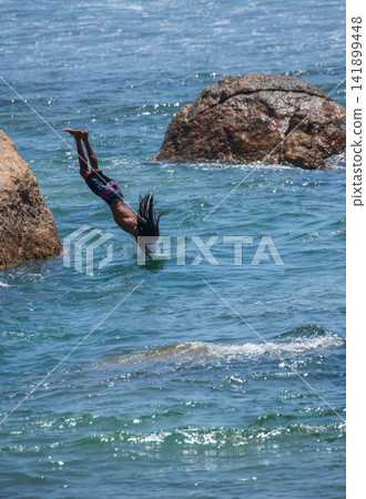 Young cliff jumper diving from rocks into the ocean at Galle Fort, Sri Lanka Young cliff jumper diving from rocks into the ocean at Galle Fort, Sri Lanka 141899448