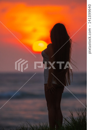 Silhouette of woman standing on beach at sunset Silhouette of woman standing on beach at sunset 141899640