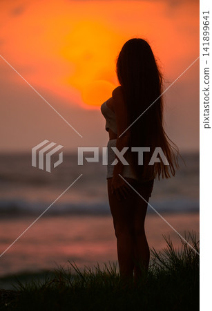 Silhouette of woman standing on beach at sunset Silhouette of woman standing on beach at sunset 141899641