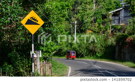 Steep downhill road warning sign with tuk-tuk on a scenic road in Nuwara Eliya, Sri Lanka Steep downhill road warning sign with tuk-tuk on a scenic road in Nuwara Eliya, Sri Lanka 141899702