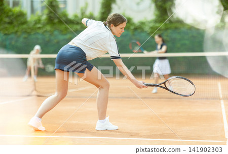 Girl plays tennis on open court with opponent Girl plays tennis on open court with opponent 141902303