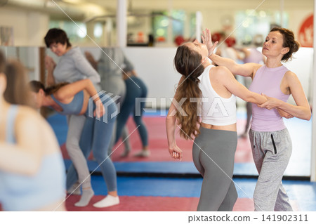 Women in pair perform effective impact on pain points while learning self-defense. Women in pair perform effective impact on pain points while learning self-defense. 141902311