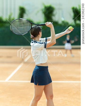 Girl plays tennis on open court with opponent Girl plays tennis on open court with opponent 141902340