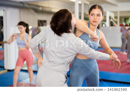 Women in pair perform effective impact on pain points while learning self-defense. 141902390