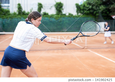 Girl plays tennis on open court with opponent 141902425