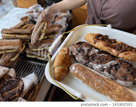 Customer Picking Fresh Baked Baguette and Salt Bread onto Tray at Bakery Customer Picking Fresh Baked Baguette and Salt Bread onto Tray at Bakery 141902501
