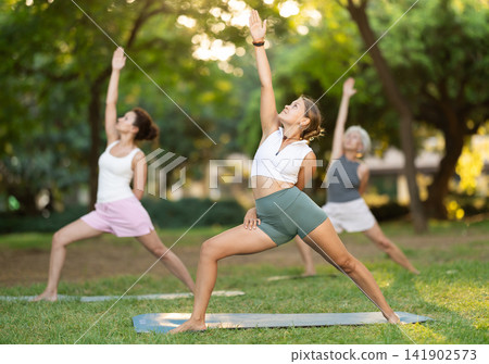 Girl performing Bound Reverse Warrior Pose during group outdoor yoga Girl performing Bound Reverse Warrior Pose during group outdoor yoga 141902573