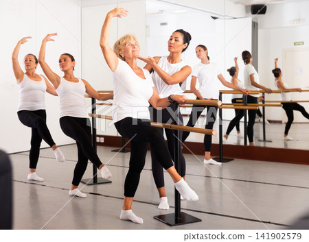 Various aged women exercising ballet moves with trainer Various aged women exercising ballet moves with trainer 141902579