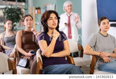 Group of women watching presentation with coach in background Group of women watching presentation with coach in background 141902613