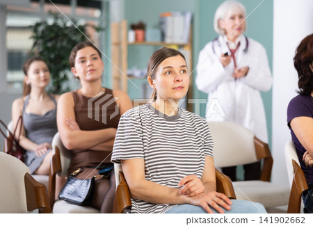 Group of women watching presentation with doctor in background Group of women watching presentation with doctor in background 141902662