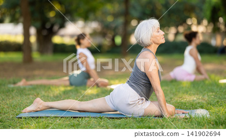 Elderly woman doing yoga in pigeon pose Elderly woman doing yoga in pigeon pose 141902694