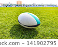 A rugby ball placed on the grass of the Paloma Mizuho Rugby Stadium court. 141902795