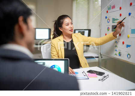 Businesswoman Presenting Financial Charts in Office Meeting Businesswoman Presenting Financial Charts in Office Meeting 141902821