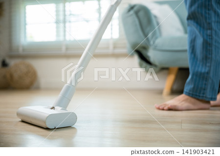 Happy Asian young woman with accumulator vacuum cleaner at home in living room Happy Asian young woman with accumulator vacuum cleaner at home in living room 141903421