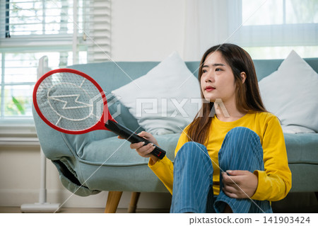 Woman killing mosquitoes hand holding fly swatter like weapon Woman killing mosquitoes hand holding fly swatter like weapon 141903424