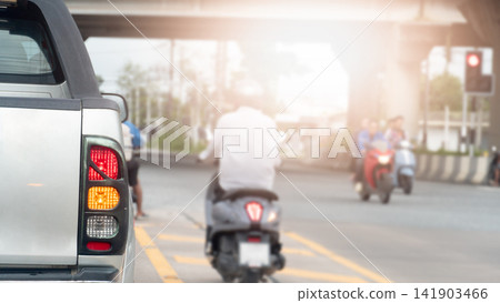 Rear view of a truck stopped in urban traffic with turn on brake light. And motorcycle rider moving ahead on the city road during a sunny daytime commute. on front with Interchange and traffic light. 141903466