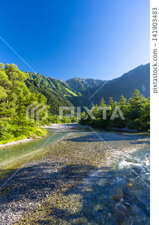 The clear waters of the Azusa River and the Hotaka mountain range as seen from Kappa Bridge in Kamikochi, surrounded by fresh greenery. The clear waters of the Azusa River and the Hotaka mountain range as seen from Kappa Bridge in Kamikochi, surrounded by fresh greenery. 141903483