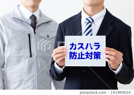 一位身穿西裝的年輕商人手持白板,上面寫著防止顧客騷擾的告示。 一位身穿西裝的年輕商人手持白板,上面寫著防止顧客騷擾的告示。 141904010