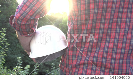 Construction worker holds a white hard hat Construction worker holds a white hard hat 141904060