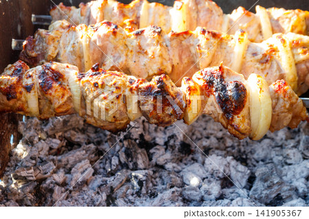 Grilled kebab cooking on metal skewer. Roasted meat cooked at barbecue.Traditional eastern dish, shish kebab. Grill on charcoal and flame, picnic, street food Grilled kebab cooking on metal skewer. Roasted meat cooked at barbecue.Traditional eastern dish, shish kebab. Grill on charcoal and flame, picnic, street food 141905367