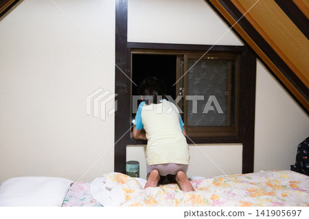 The back of a child looking out the small window of the lodge. The back of a child looking out the small window of the lodge. 141905697