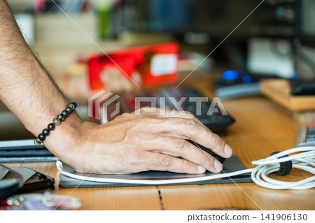 a hand using a computer mouse on a wooden desk, highlighting everyday computer work, office productivity, digital workflow, and modern workspace. 141906130