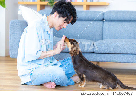 與狗相伴的家庭生活;一位男士正在訓練一隻狗。 與狗相伴的家庭生活;一位男士正在訓練一隻狗。 141907468