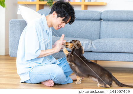 與狗相伴的家庭生活;一位男士正在訓練一隻狗。 與狗相伴的家庭生活;一位男士正在訓練一隻狗。 141907469