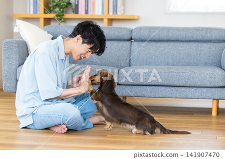 與狗相伴的家庭生活；一位男士正在訓練一隻狗。 141907470