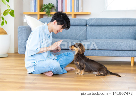 與狗相伴的家庭生活;一位男士正在訓練一隻狗。 與狗相伴的家庭生活;一位男士正在訓練一隻狗。 141907472