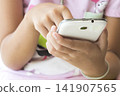 hand of children girl holding mobile phone playing a game  141907565