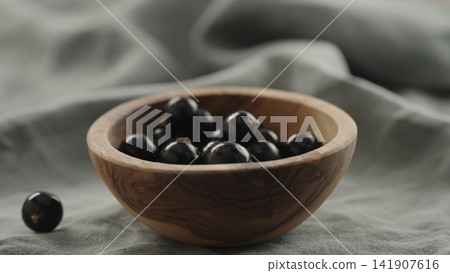ripe blackcurrant falling in wood bowl 141907616