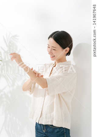 一位三十多歲的女性正在保養她的手臂。 141907648