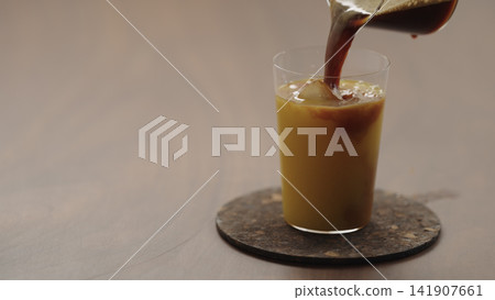 pour espresso in glass with orange juice to make Bumble coffee pour espresso in glass with orange juice to make Bumble coffee 141907661