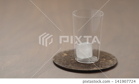 add ice in a glass on a wood table 141907724