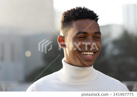 African American man smiling and glancing left on rooftop wearing white turtleneck sweater African American man smiling and glancing left on rooftop wearing white turtleneck sweater 141907775
