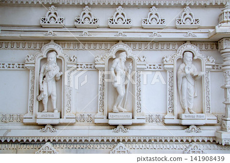 A white marble sculpture of a Hindu saint in the temple. Oldest temple in India. Beautiful sculpture of ancient India 13th century. Wall mounting background. Wall poster. A white marble sculpture of a Hindu saint in the temple. Oldest temple in India. Beautiful sculpture of ancient India 13th century. Wall mounting background. Wall poster. 141908439