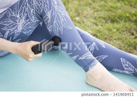 Young woman using a fascia release gun and massage gun outdoors Young woman using a fascia release gun and massage gun outdoors 141908451