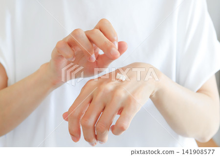 A woman moisturizing her hands with hand cream. 141908577