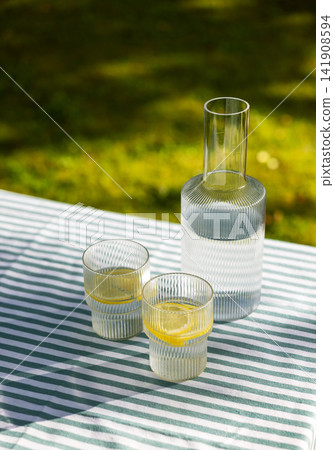 Refreshing Lemon Water on Garden Table in Sunny Summer Backyard Refreshing Lemon Water on Garden Table in Sunny Summer Backyard 141908594