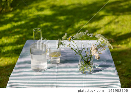 Refreshing Lemon Water on Garden Table in Sunny Summer Backyard Refreshing Lemon Water on Garden Table in Sunny Summer Backyard 141908596