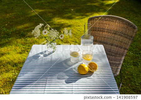Refreshing Lemon Water on Garden Table in Sunny Summer Backyard Refreshing Lemon Water on Garden Table in Sunny Summer Backyard 141908597