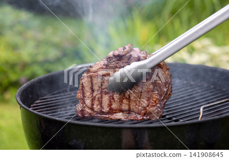 Juicy Beef Steak Grilling on Charcoal Barbecue in Garden Juicy Beef Steak Grilling on Charcoal Barbecue in Garden 141908645