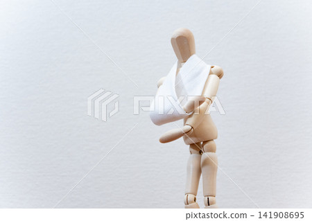 A drawing mannequin with a triangular bandage on its arm. 141908695